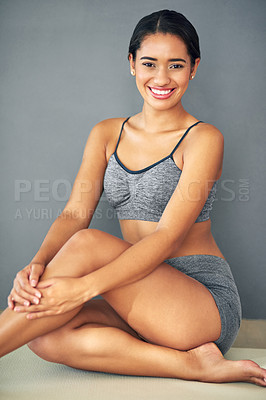 Buy stock photo Shot of a sporty young woman sitting against a grey background