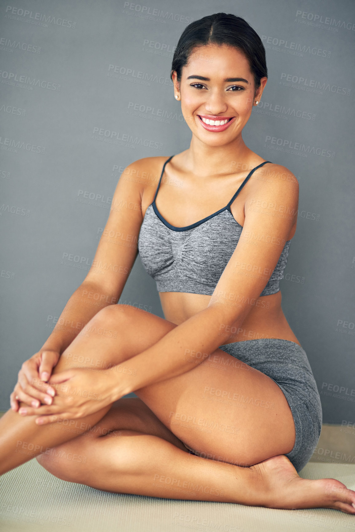 Buy stock photo Shot of a sporty young woman sitting against a grey background