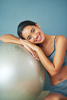 Buy stock photo Shot of a sporty young woman leaning against a pilates ball