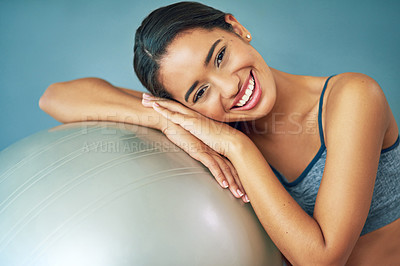 Buy stock photo Shot of a sporty young woman leaning against a pilates ball