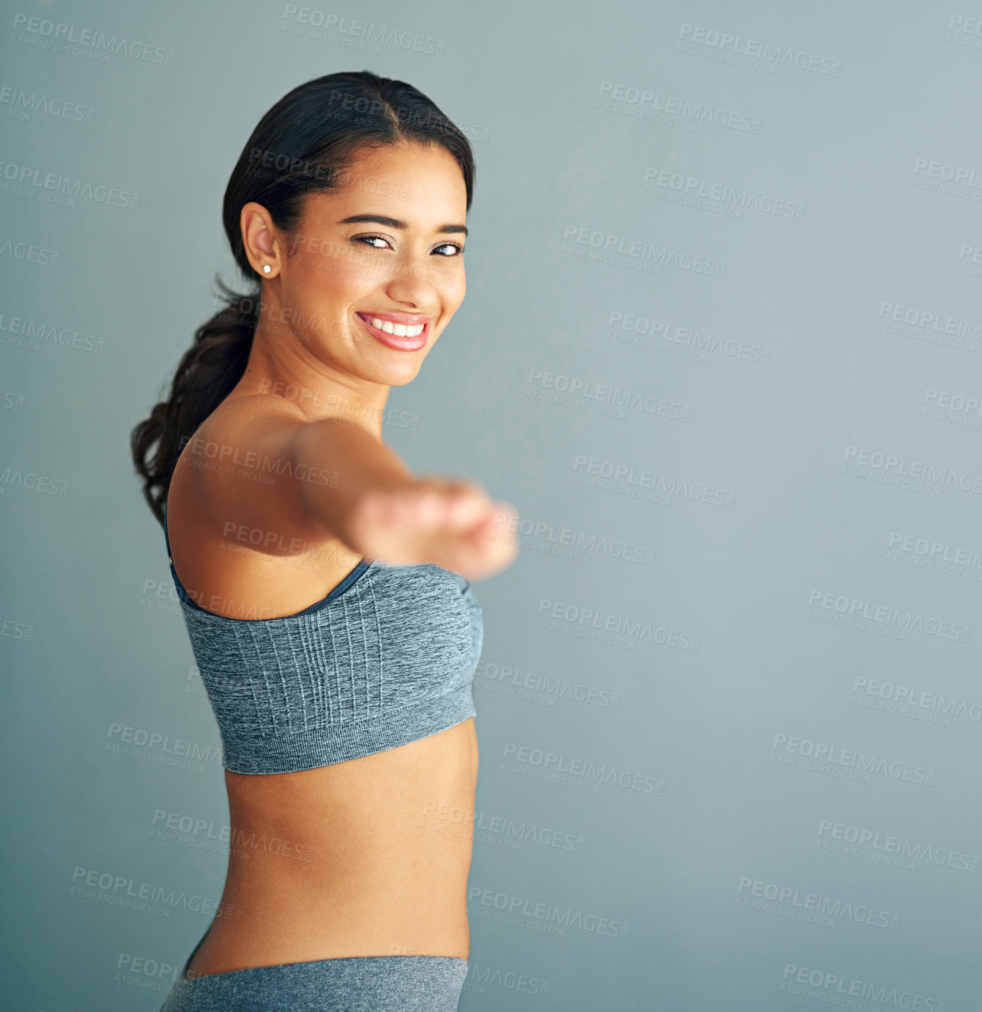 Buy stock photo Cropped shot of a young woman stretching against a grey background
