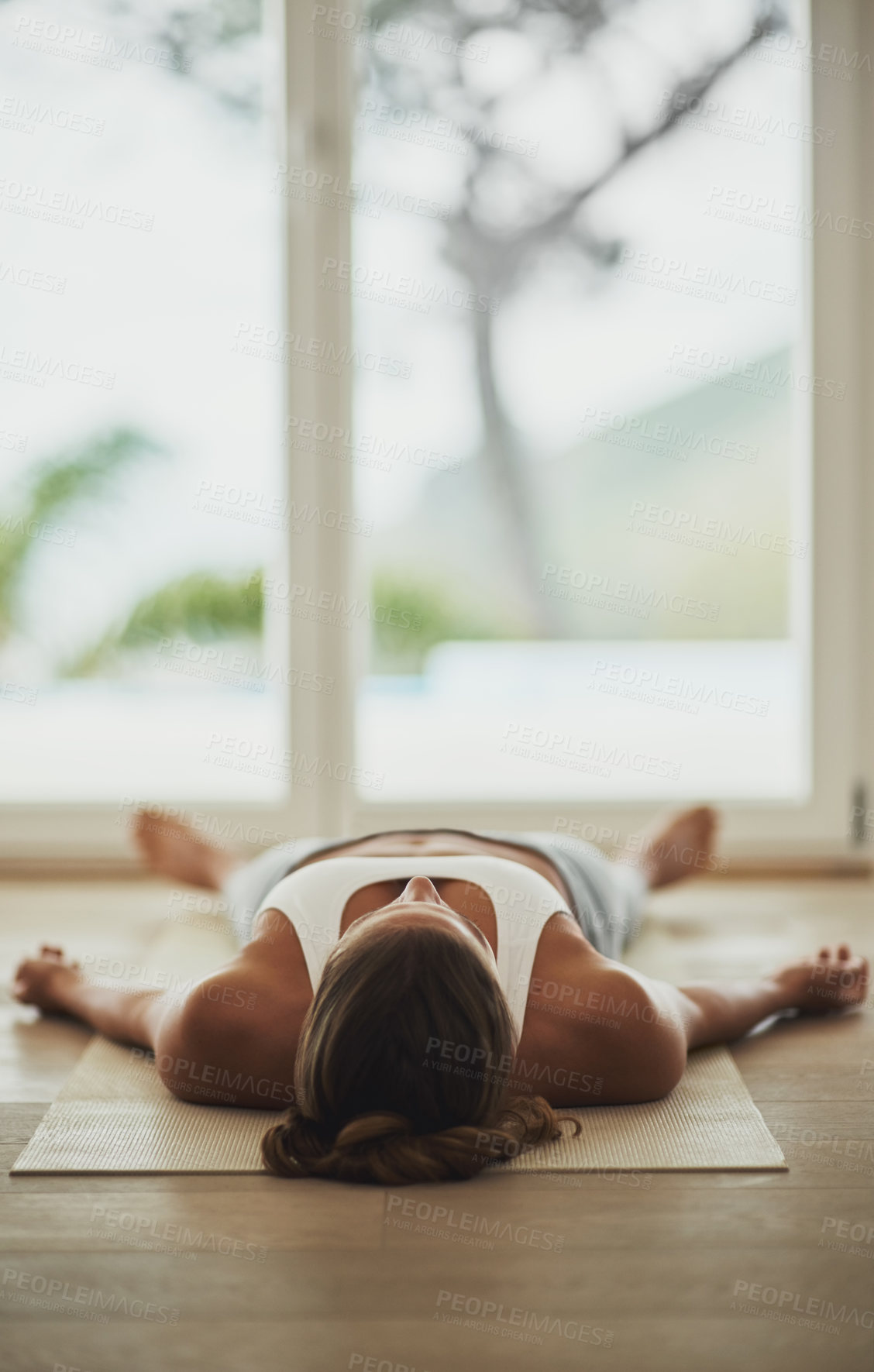 Buy stock photo Shot of a young woman lying on her yoga mat after a workout