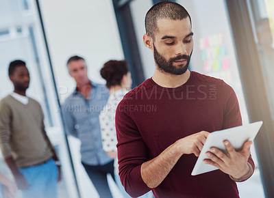 Buy stock photo Cropped shot of a young businessman working in the office with her colleagues in the background