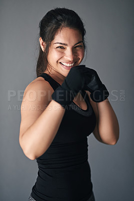 Buy stock photo Woman, portrait and fist in studio for training, cardio boxing and ready for fight tournament with power. Girl, happy and gray background for self defense with wellness, combat workout and endurance.