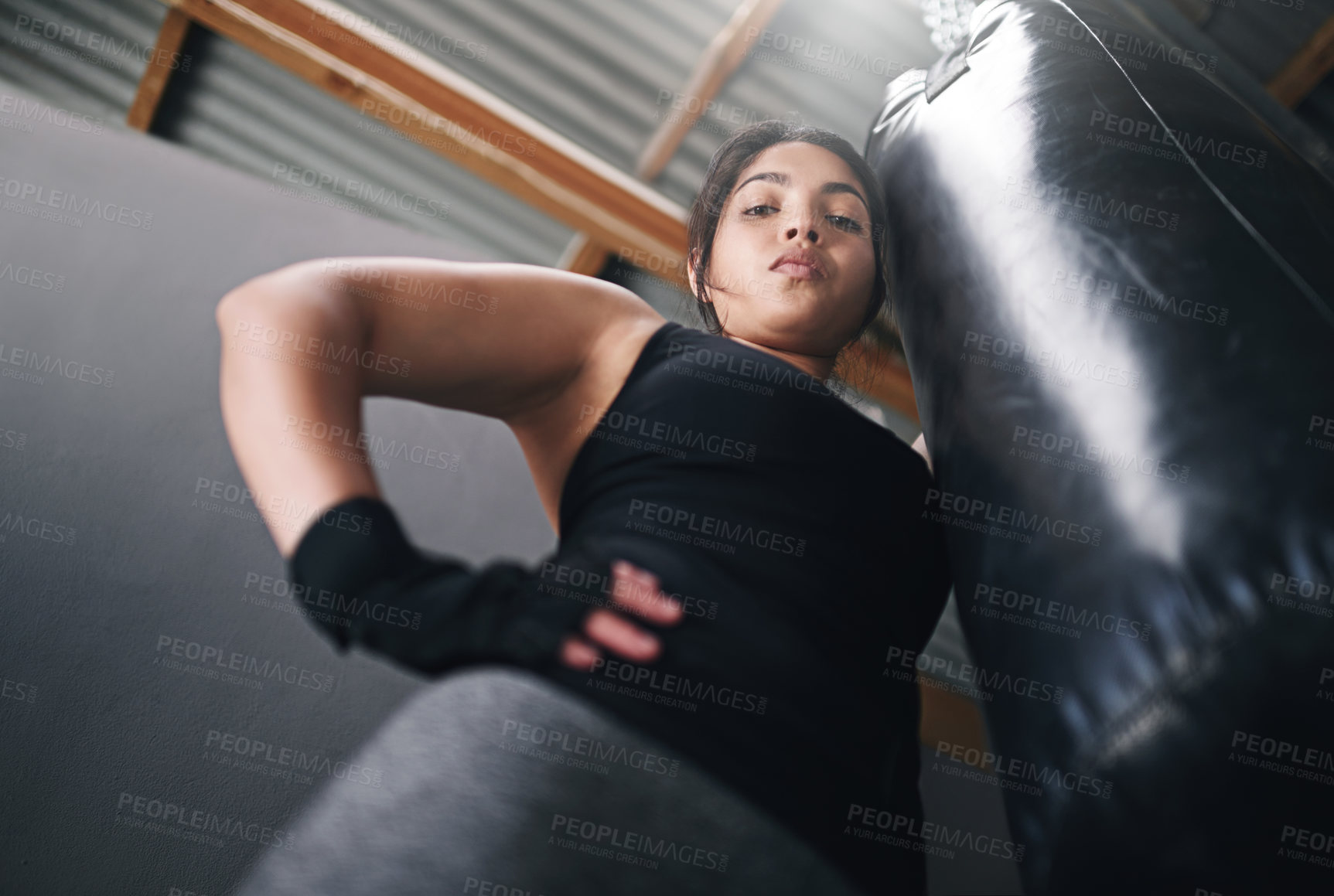 Buy stock photo Woman, portrait and punching bag in gym for training, cardio boxing and building endurance for strength. Girl, serious and low angle for self defense, adrenaline control and combat workout for sport.