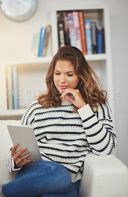 Buy stock photo Shot of a young woman using her digital tablet on the sofa at home