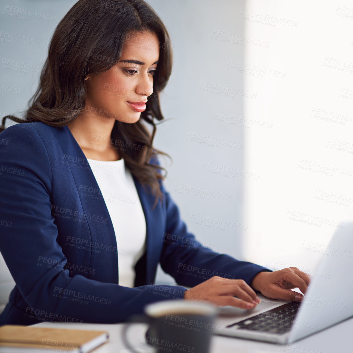 Buy stock photo Cropped shot of a young businesswoman working on her laptop