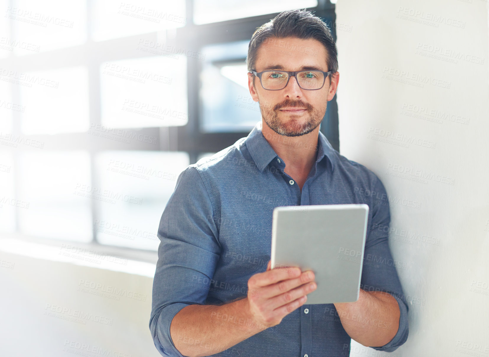 Buy stock photo Cropped portrait of a businessman working on his tablet in the office