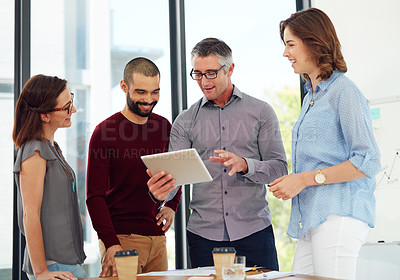 Buy stock photo Shot of a group of businesspeople discussing something on a digital tablet