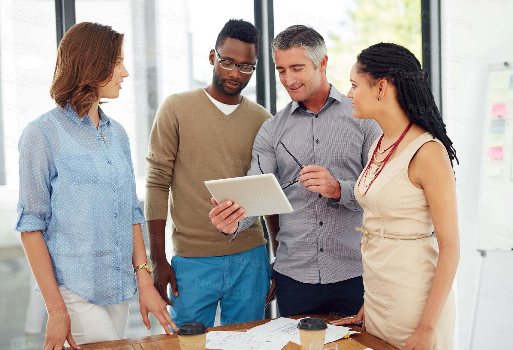 Buy stock photo Shot of a group of businesspeople discussing something on a digital tablet