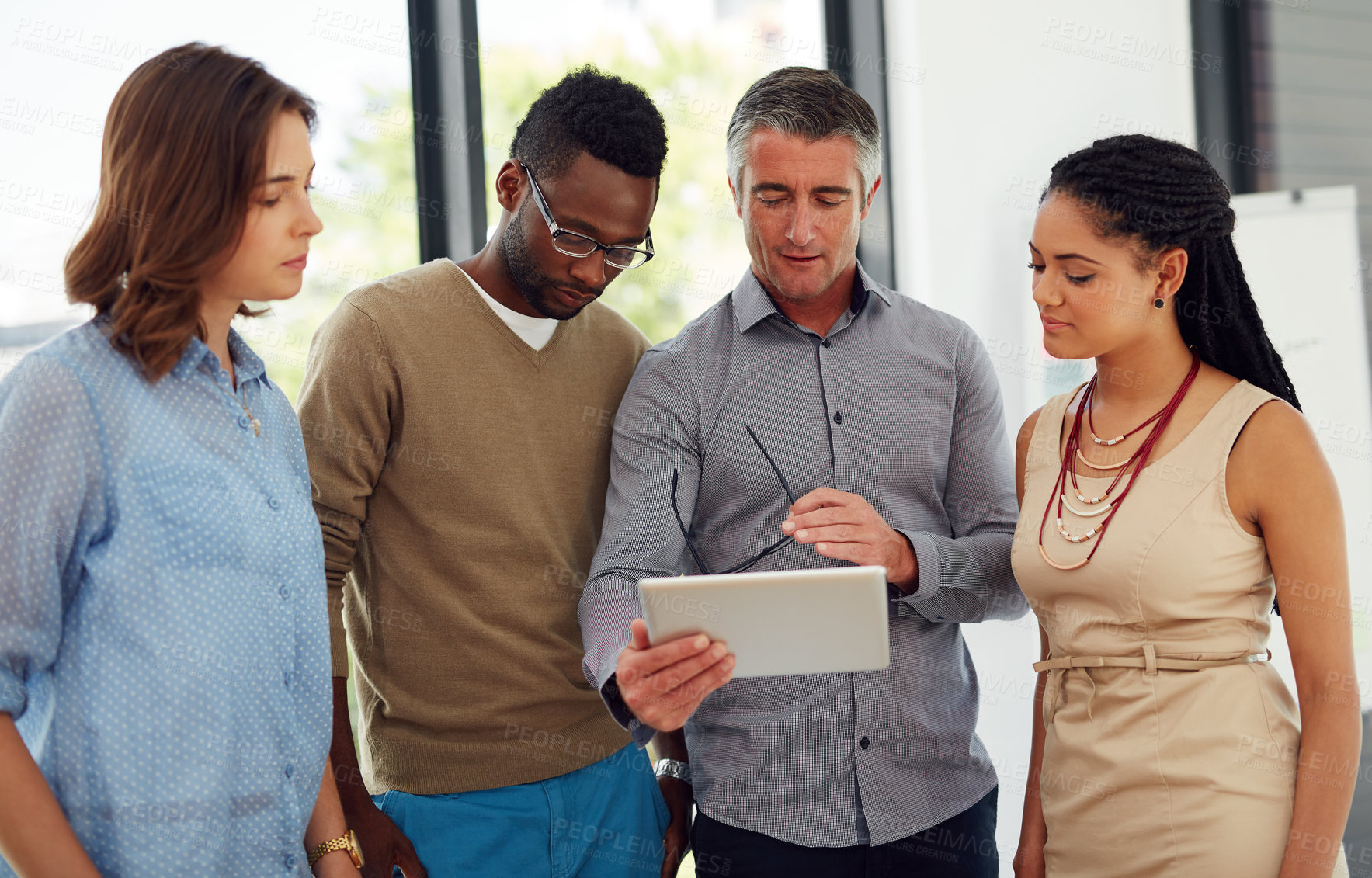 Buy stock photo Shot of a group of businesspeople discussing something on a digital tablet