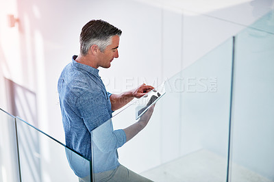 Buy stock photo Shot of a mature businessman using a digital tablet on the stairs in a modern office