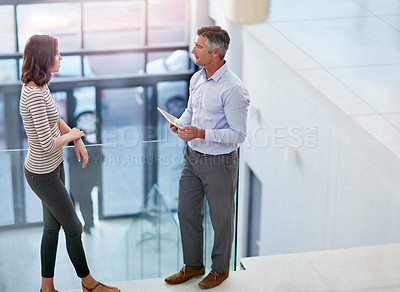 Buy stock photo High angle shot of two businesspeople talking in the lobby of their office