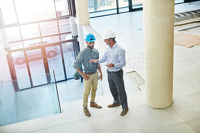 Buy stock photo High angle shot of two businessmen talking in the lobby of their office