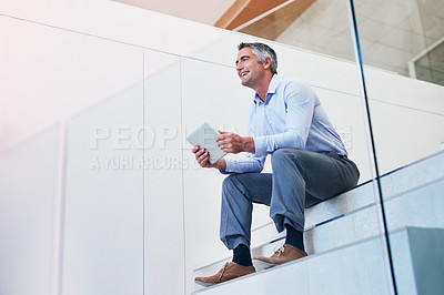 Buy stock photo Shot of a mature businessman using a digital tablet on the stairs in a modern office