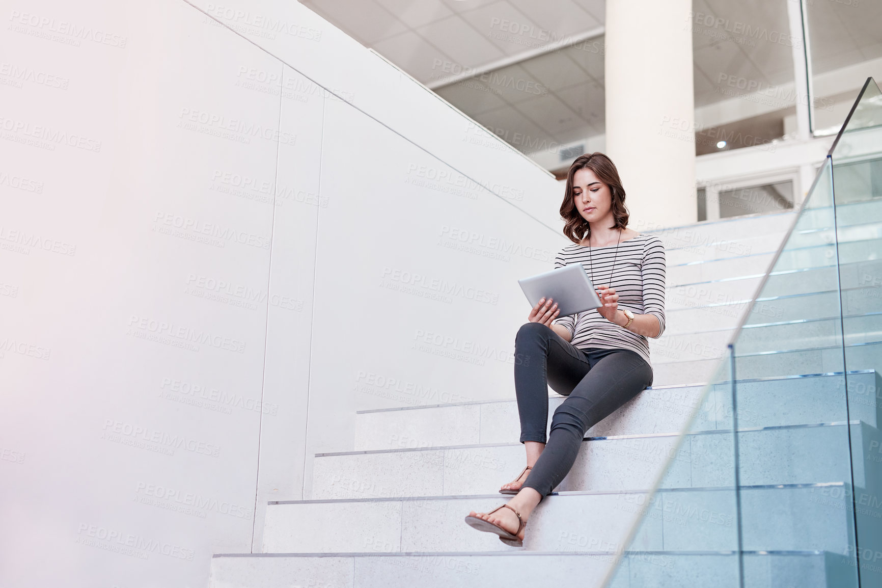 Buy stock photo Shot of a young businesswoman using a digital tablet on the stairs in a modern office