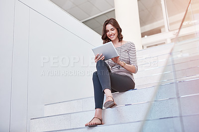 Buy stock photo Shot of a young businesswoman using a digital tablet on the stairs in a modern office