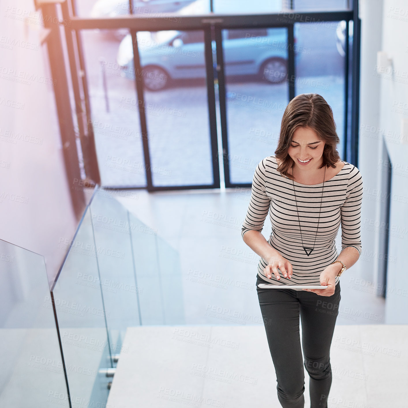 Buy stock photo Business, woman and walking in stairs with tablet on break for social media post and interaction. Female person, employee and happy or laughing at office with online videos, memes and communication