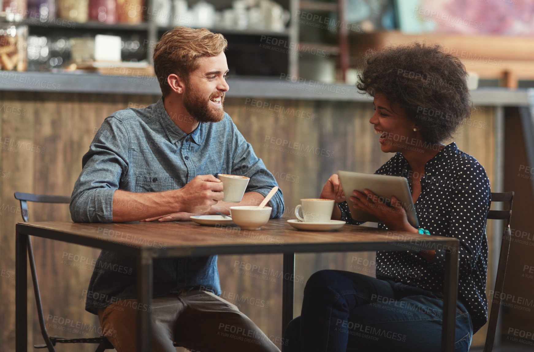 Buy stock photo Shot of a young couple using a digital tablet together on a coffee date