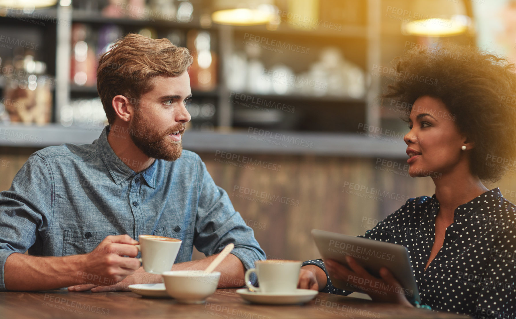 Buy stock photo Chat, man and woman in cafe with tablet, social media and relax for networking connection at table. Date, conversation and interracial couple in coffee shop with online digital app, drink and talking