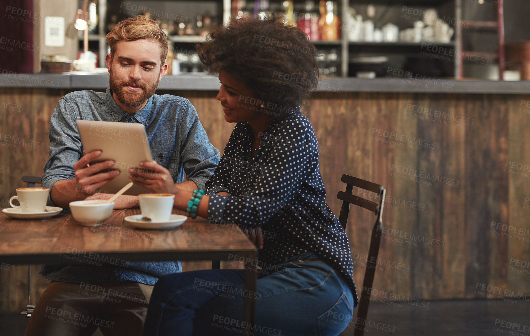 Buy stock photo Shot of a young couple using a digital tablet together on a coffee date