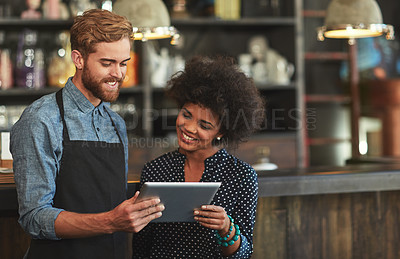 Buy stock photo Shot of young coffee shop workers using a digital tablet together