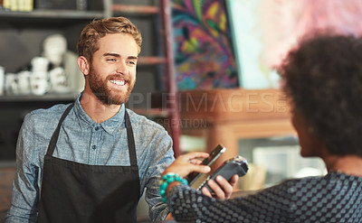 Buy stock photo Shot of a barista taking a smartphone payment from a customer at a cafe