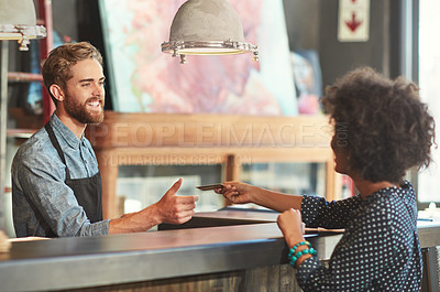 Buy stock photo Shot of a barista taking a credit card payment from a customer at a cafe