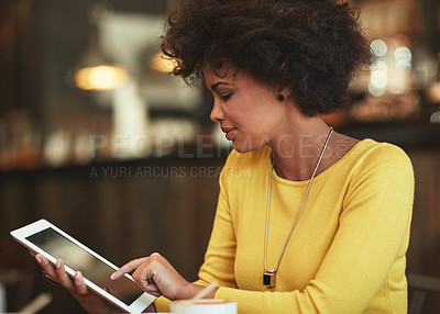 Buy stock photo Shot of a young woman using a digital tablet in a cafe