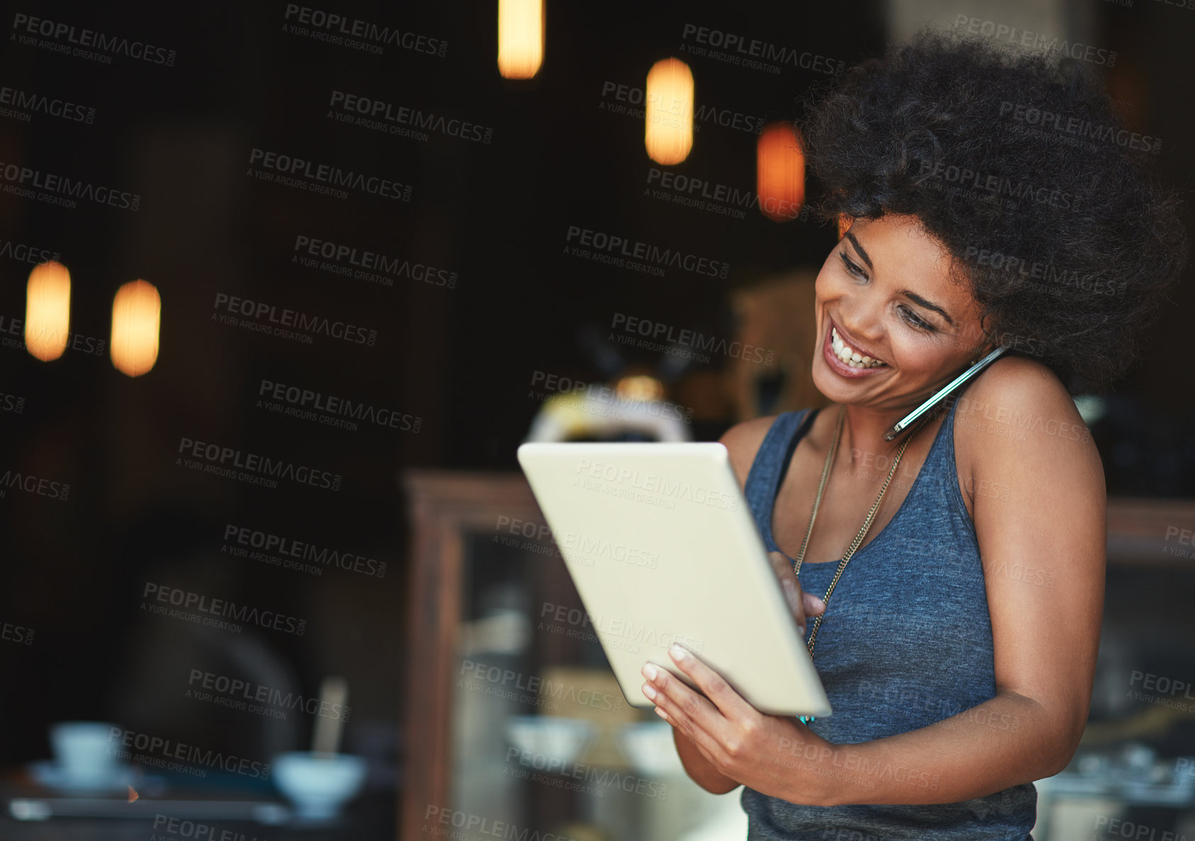 Buy stock photo Shot of a young woman using a digital tablet while talking on the phone at a cafe