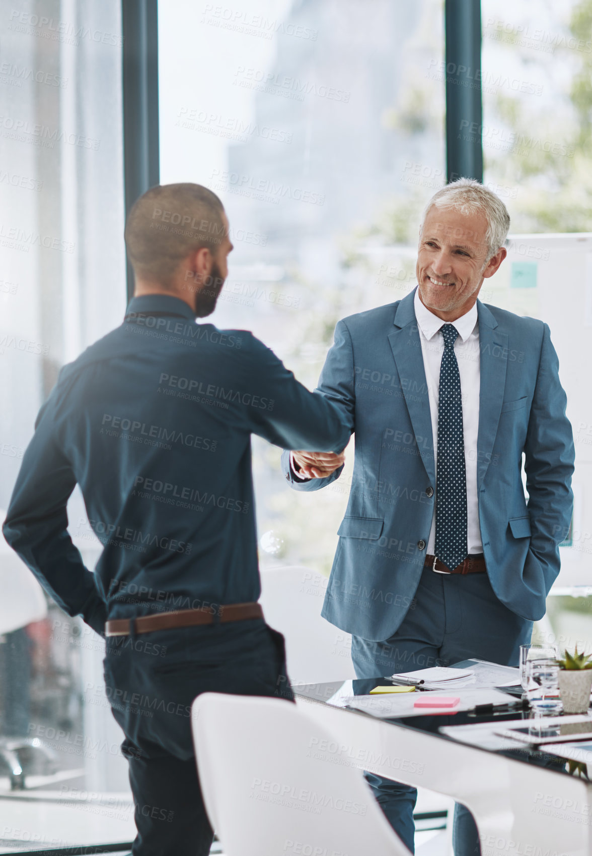 Buy stock photo Cropped shot of two businessmen shaking hands in the office