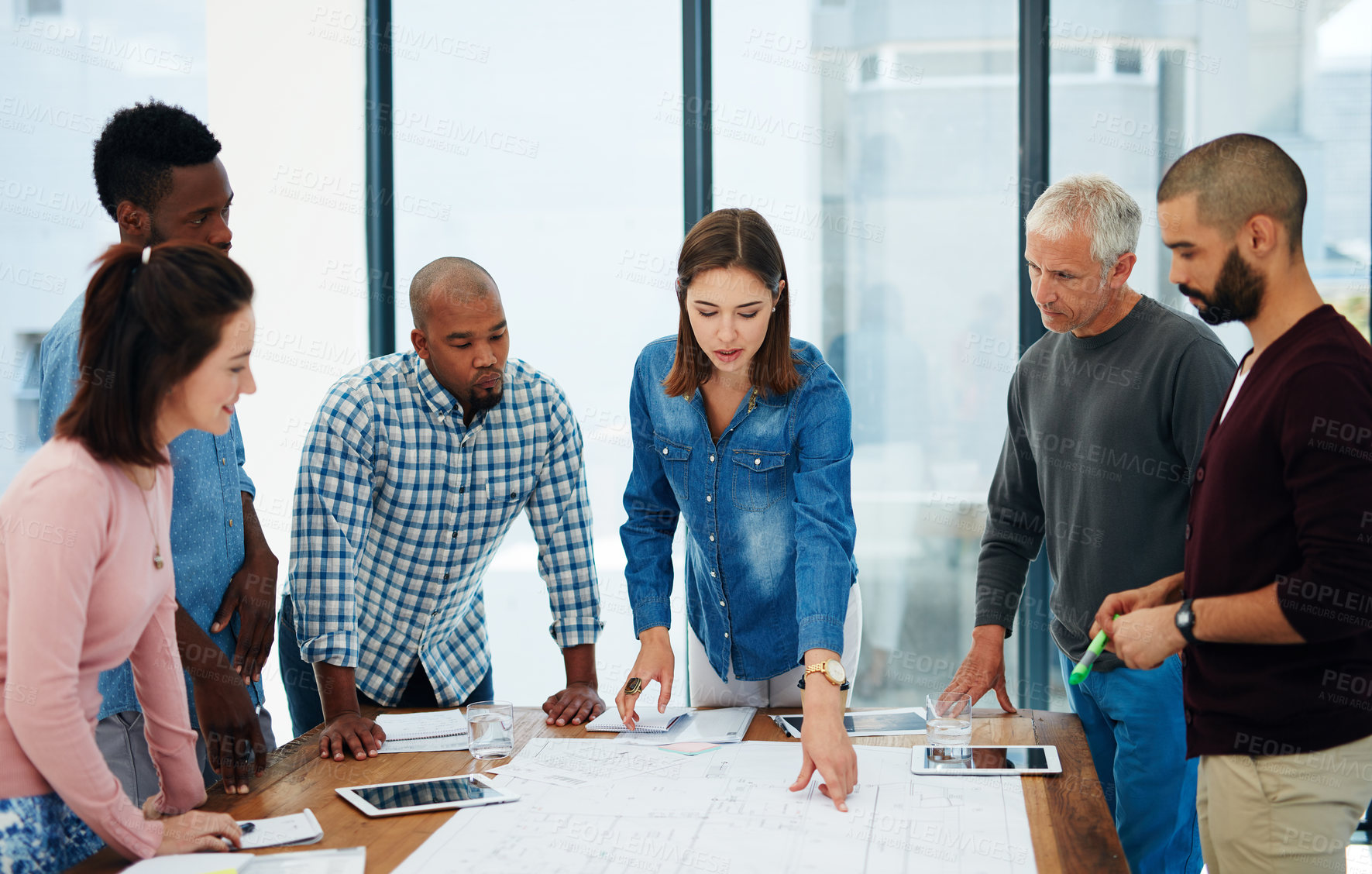 Buy stock photo Woman, architect and documents with team in meeting for planning, brainstorming or civil engineering at office. Young female person with group, paperwork or floor layout for construction at workplace