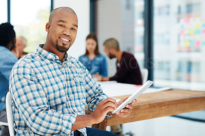 Buy stock photo Portrait of a young man using his  tablet with his colleagues sitting in the background