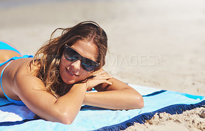 Buy stock photo Shot of a young woman lying on the beach on a summers day
