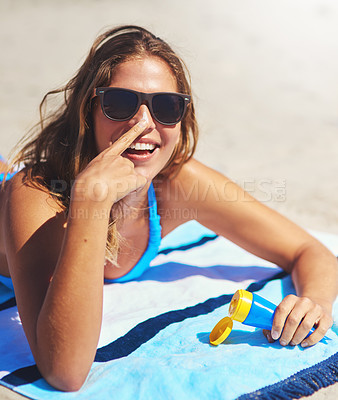 Buy stock photo Shot of a young woman applying suntan lotion at the beach