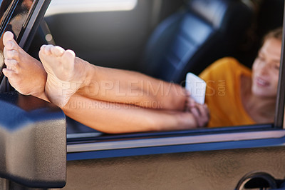 Buy stock photo Shot of a young woman using her cellphone while sitting in her car