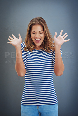 Buy stock photo Studio shot of a young woman looking excited against a gray background