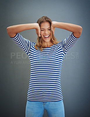 Buy stock photo Studio shot of a young woman covering her ears against a gray background