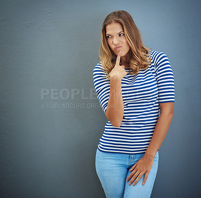 Buy stock photo Studio shot of a young woman looking unsure against a gray background