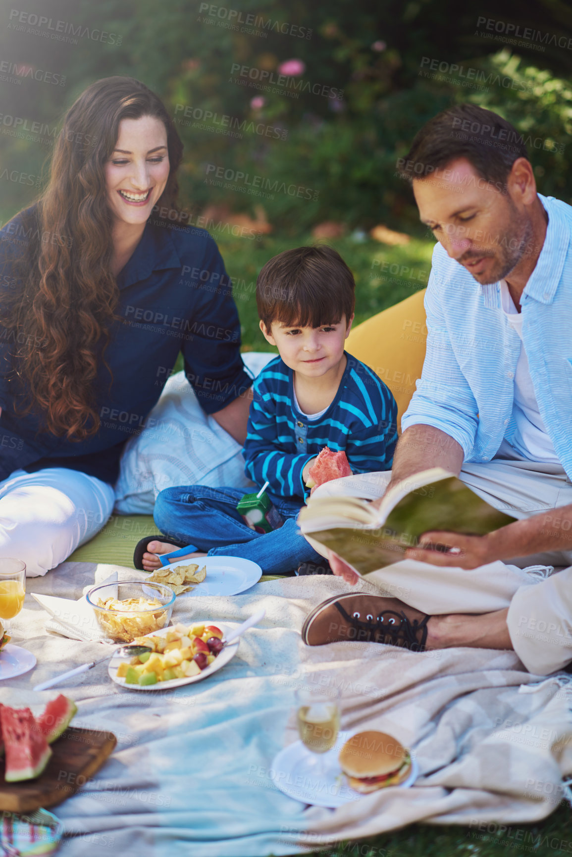 Buy stock photo Kid, picnic and parents reading book at park, eating lunch and happy family bonding together in summer. Mother, child and father storytelling outdoor for learning with food, relax and healthy meal