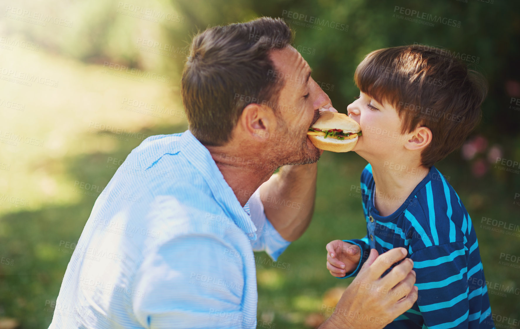 Buy stock photo Cropped shot of a father and son eating a burger outside