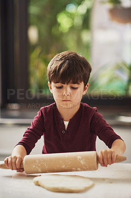 Buy stock photo Shot of a young boy rolling dough in the kitchen