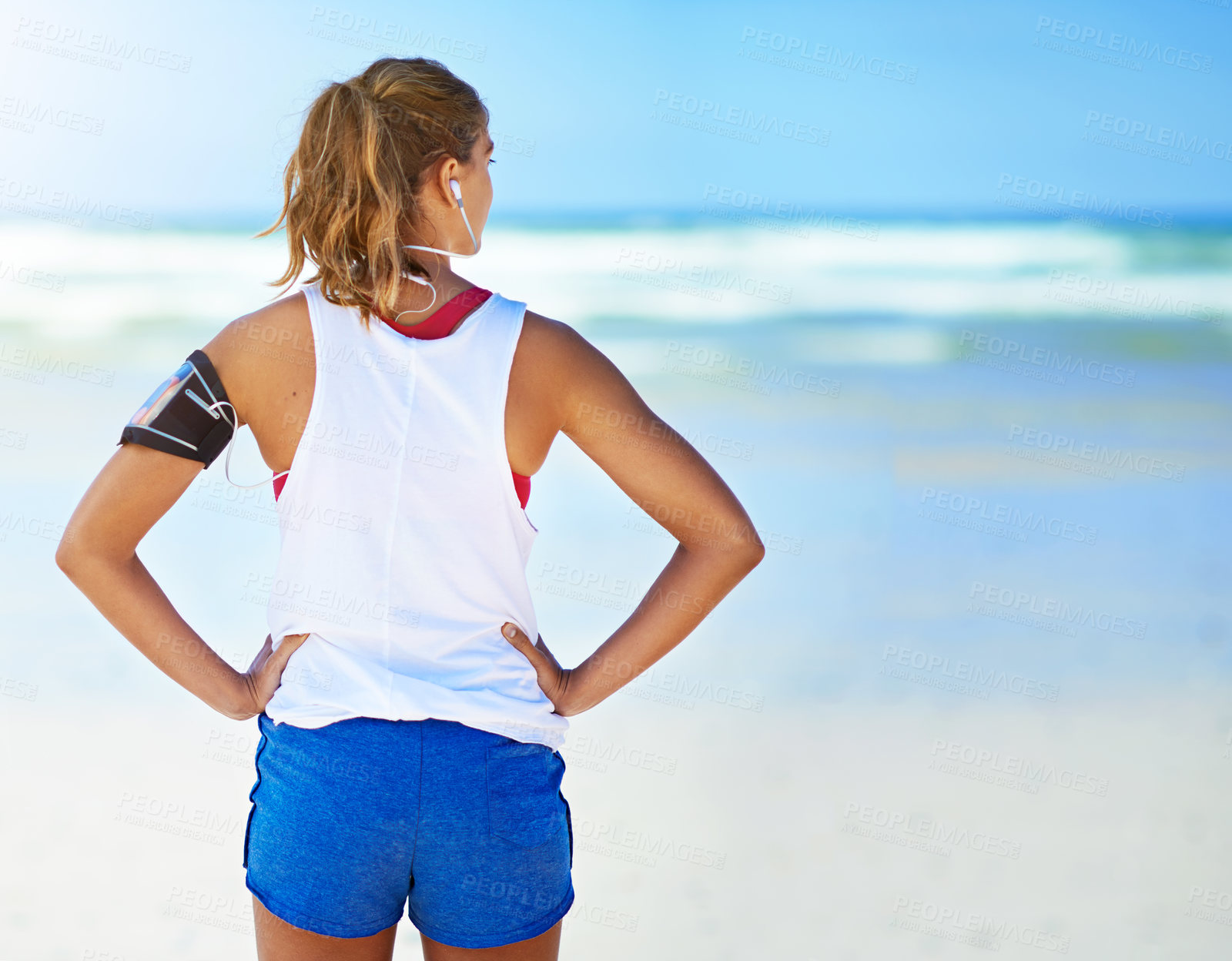Buy stock photo Rearview shot of a young woman standing with her hands on her hips on the beach