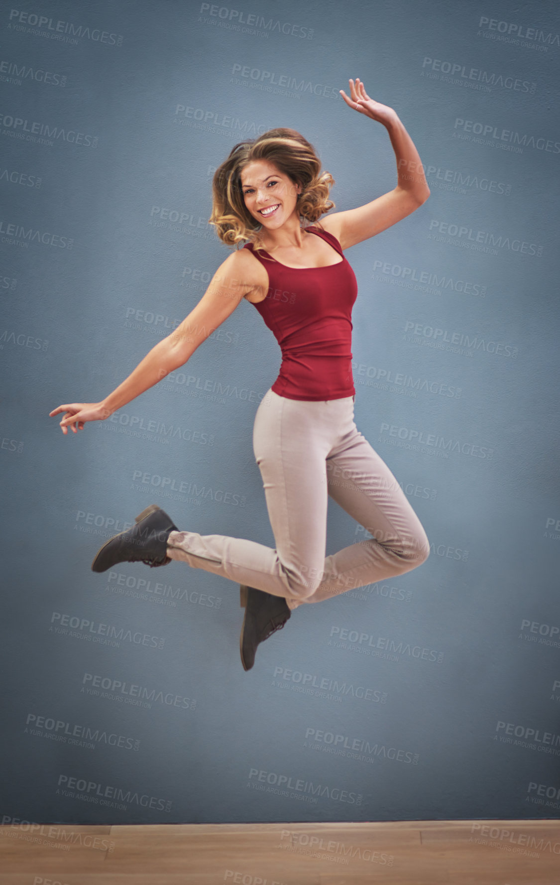 Buy stock photo Shot of a happy young woman jumping in the air against a gray background