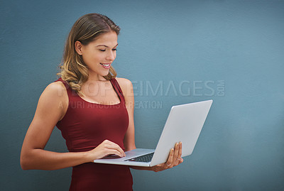 Buy stock photo Shot of a young woman holding a laptop against a gray background