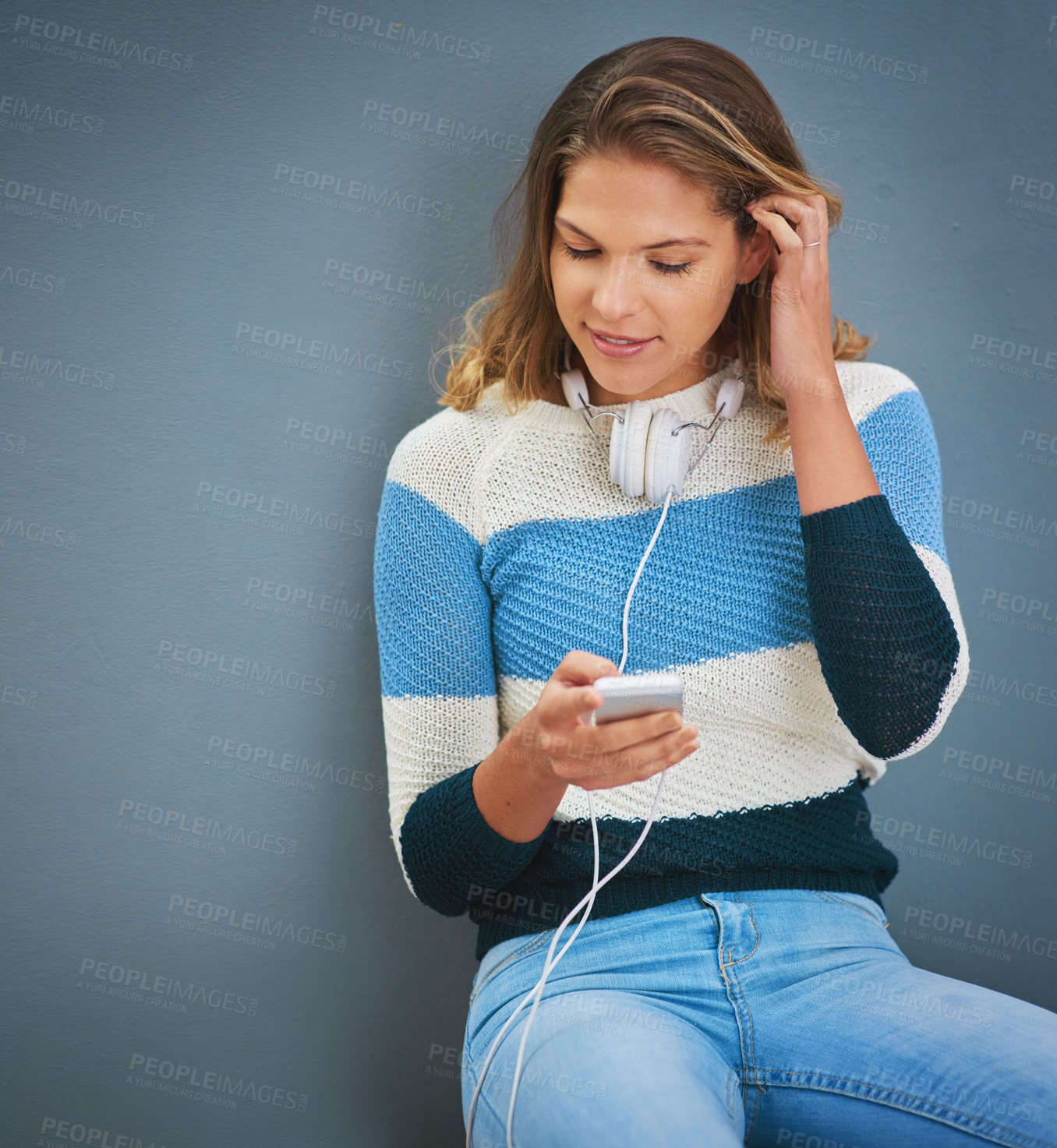 Buy stock photo Woman, phone and headphones in studio for music, texting and reading notification by background. Person, smartphone and audio streaming with subscription, contact and check on mobile app with chat