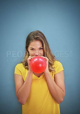 Buy stock photo Shot of a young woman inflating a balloon against a grey background