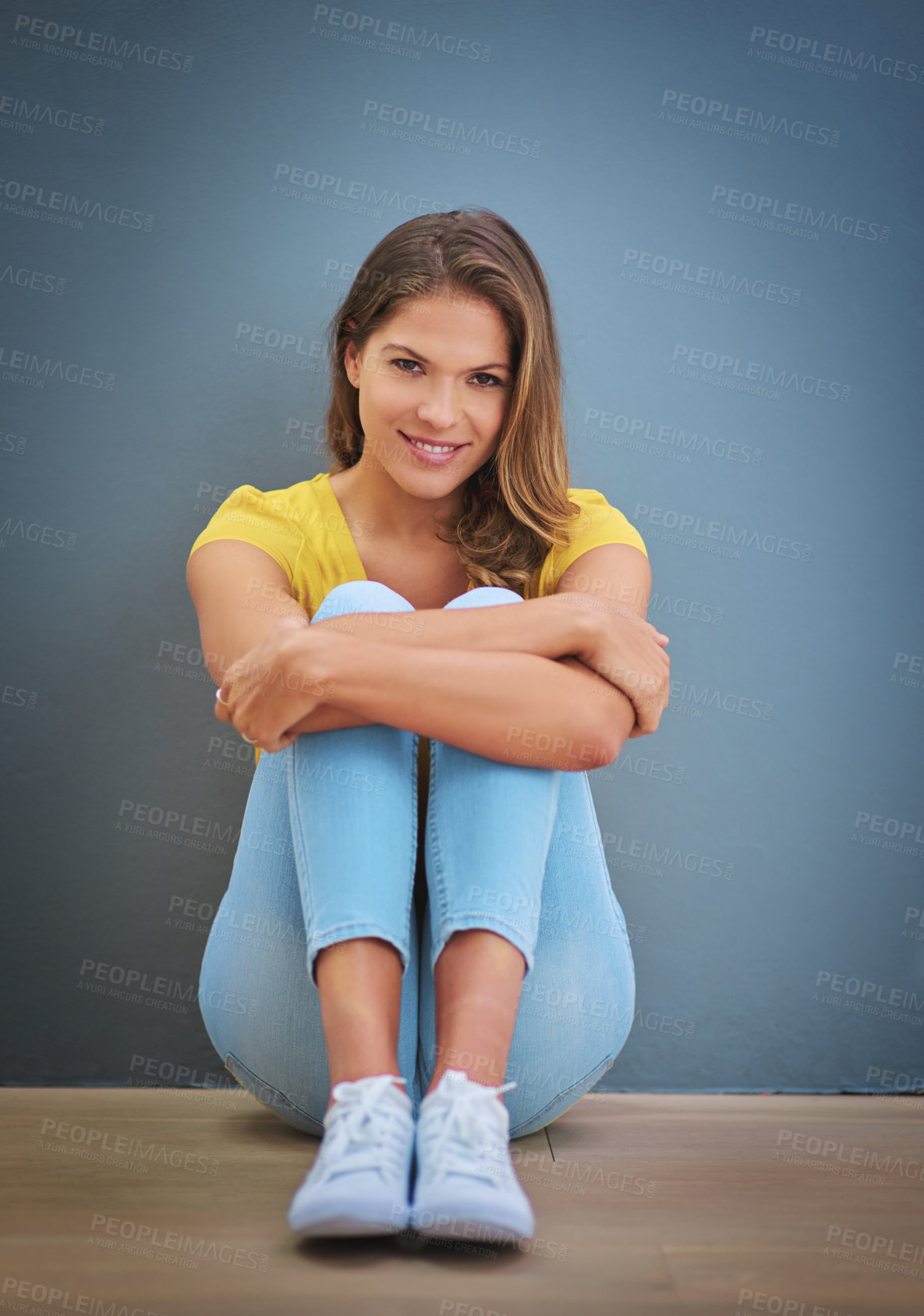 Buy stock photo Woman, face and relax by blue wall with smile for leisure, calm and positive attitude on weekend. Female person, portrait and chill on floor or ground with happiness for comfort, peace and sitting