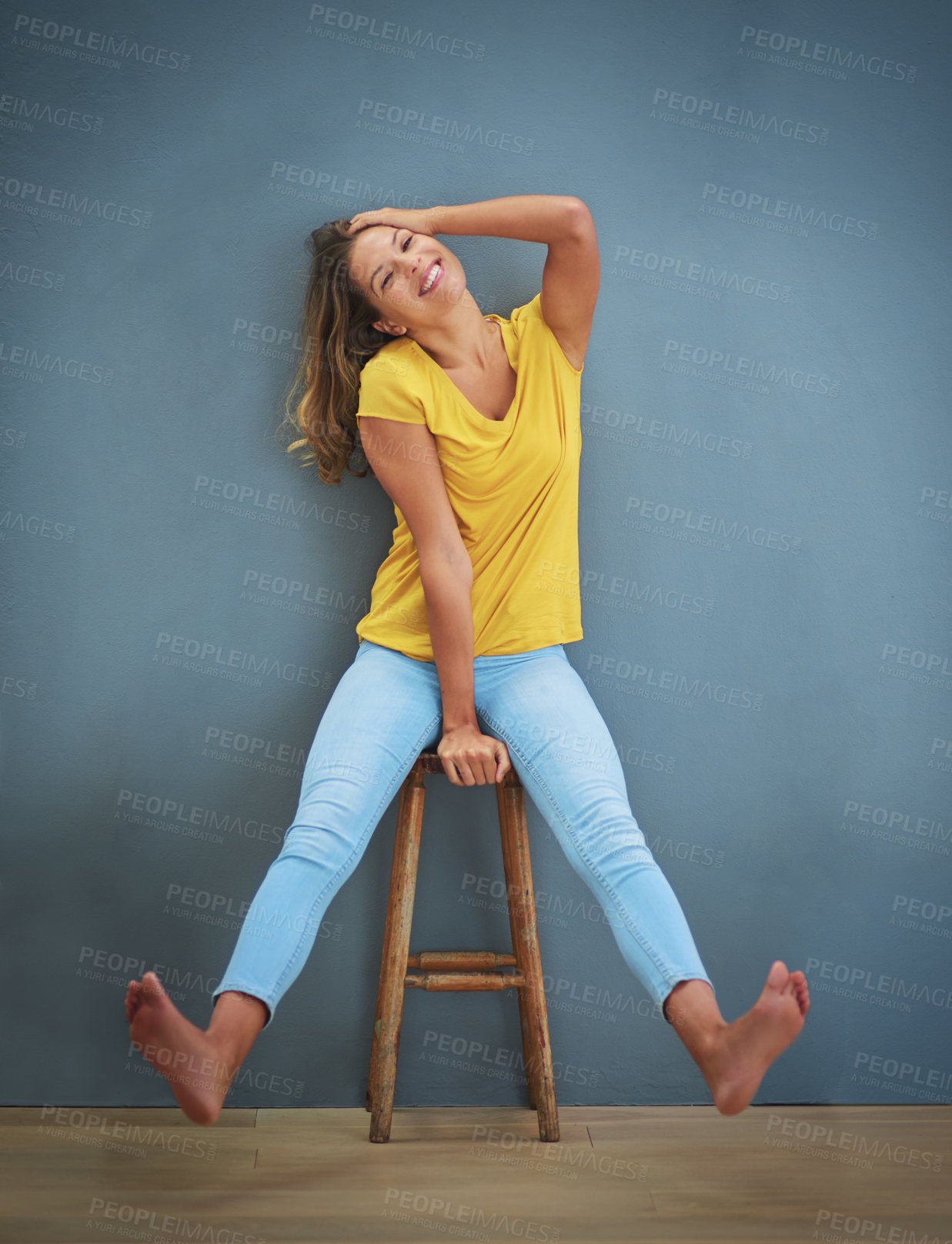 Buy stock photo Shot of a young woman sitting on a chair against a gray wall