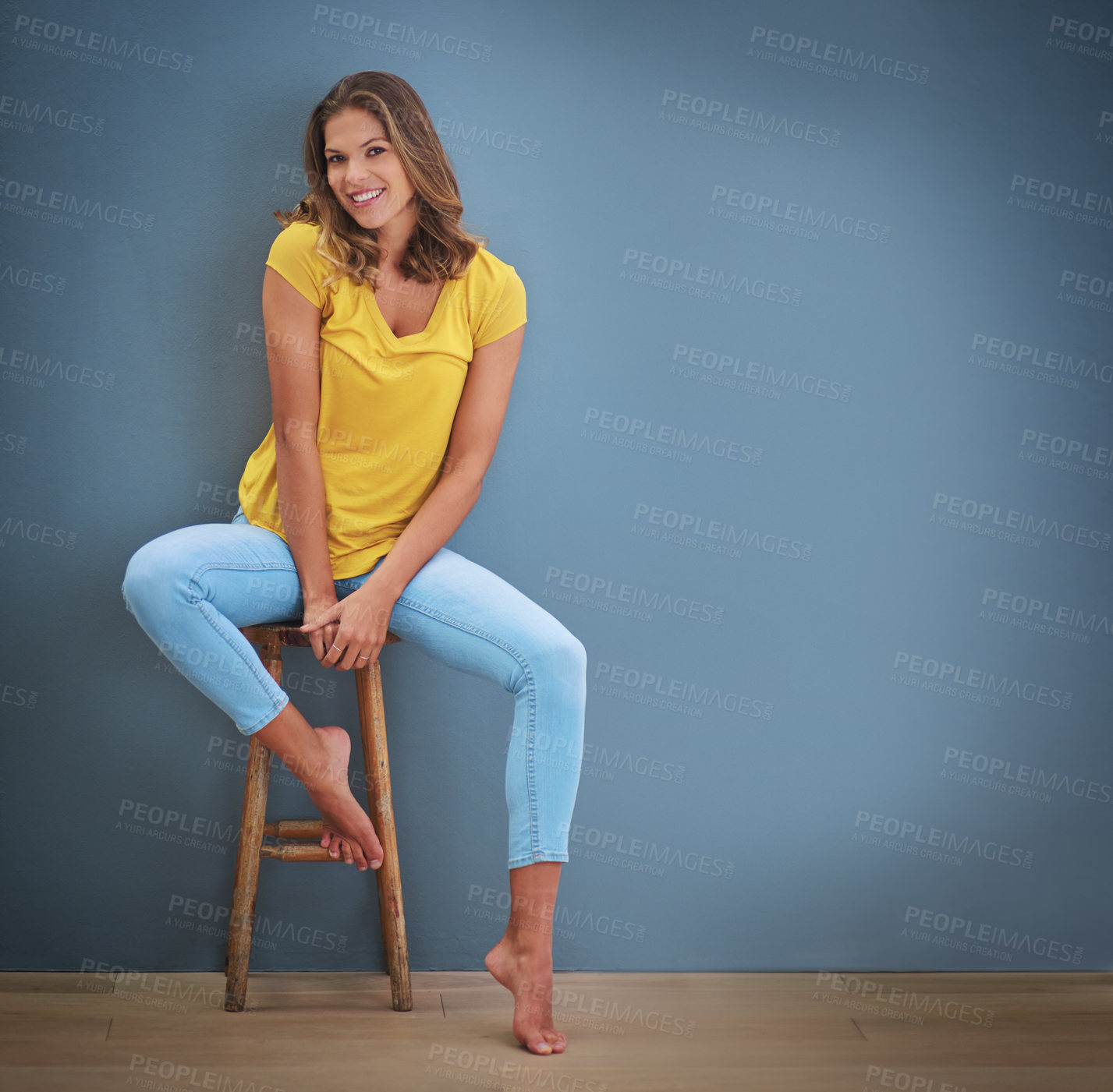 Buy stock photo Shot of a young woman sitting on a chair against a gray wall